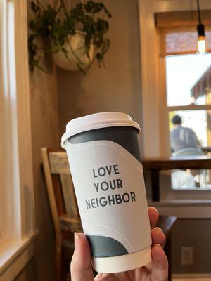 Hot chocolate in disposable cup that says "Love Your Neighbor."