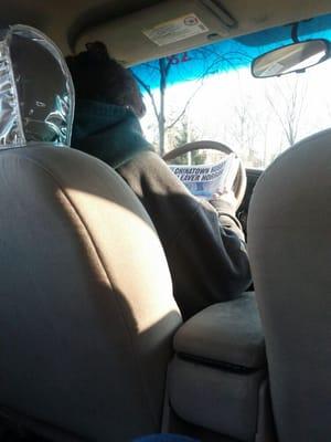 Female driver reading the newspaper while at a red light.