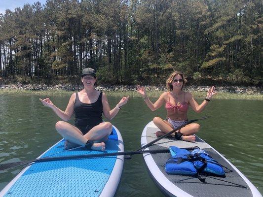 Two people seated on stand up paddle boards in Rudee Inlet, Virginia Beach, VA