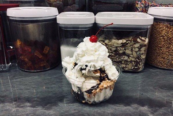 Two scoops of super premium ice cream topped with hot fudge, whipped cream, peanuts and a cherry