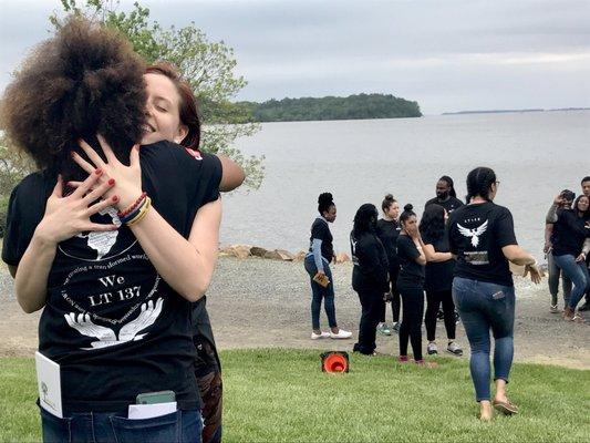 Service team members embrace after a powerful residential weekend with Leadership Team 158 (pictured in the background)