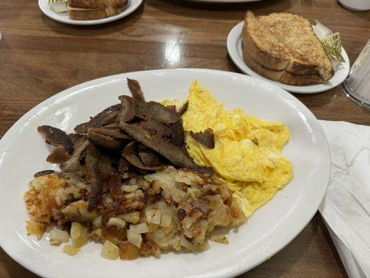 Two eggs with gyro meat, home fries and rye toast.