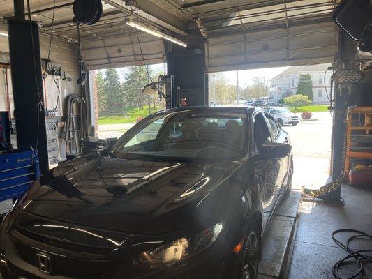 A Honda geta loaded on the rack for a routine oil change