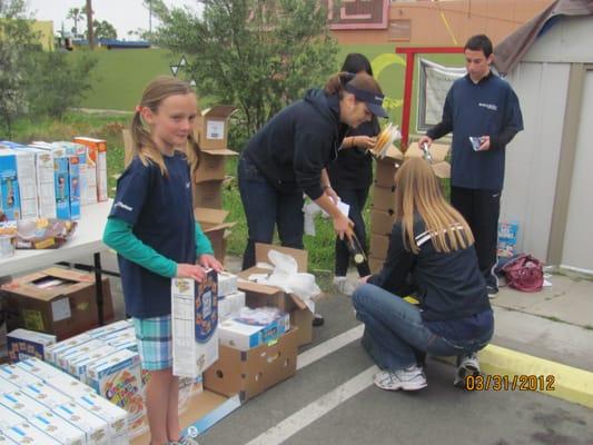 Volunteers helping to stuff bags full of food for kids and families