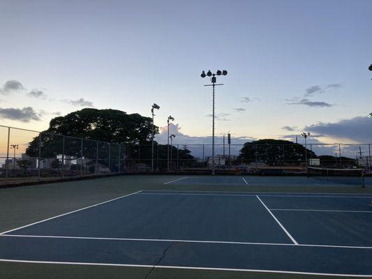 Tennis courts with huge cracks overlooking the basketball courts and the pool