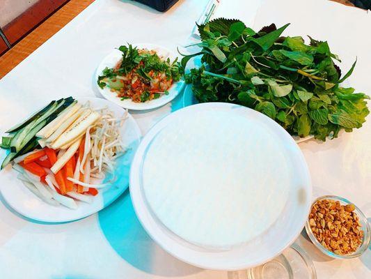 All the things you need to make your wrap with (herbs, carrots, radish, sprouts, wrapper, hot water, etc.).