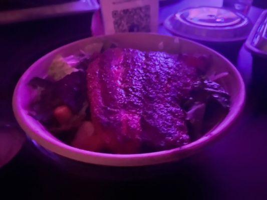 Salmon and Caesar salad served in a paper bowl.