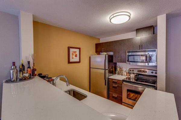 Staged kitchen with stainless steel appliances and quartz countertops.