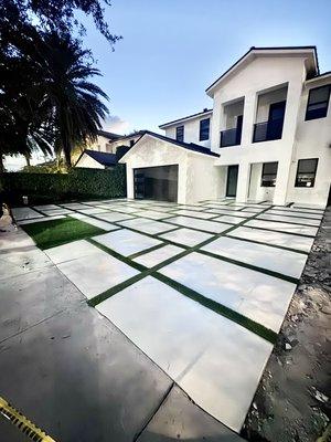 Concrete driveway with artificial turf and sealer.