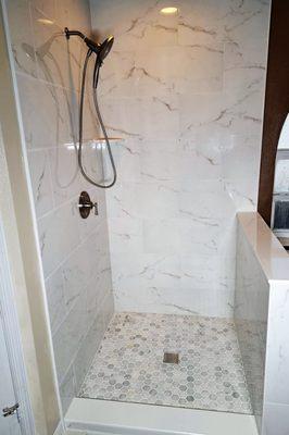 New shower with 12" x 24" high polish porcelain tiles, tumbled marble floor with square drain and nickel fixtures.