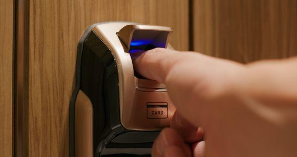 Individual using a fingerprint scanner on a door lock in Colleyville, TX, for secure access.