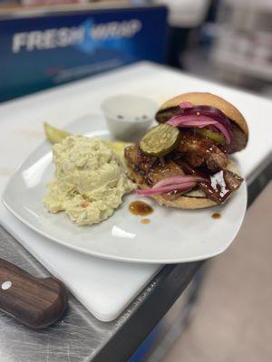 Brisket sandwich, with potato salad and pickled red onion with pickles.