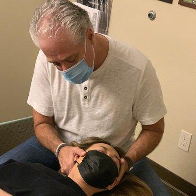 Dr. Cook adjusting a patient's neck to relieve her from pain and discomfort related to work stress