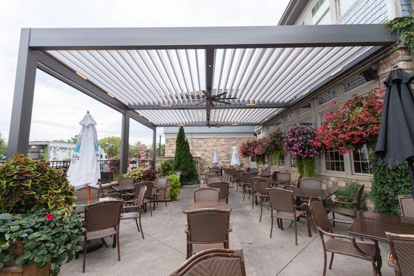 Aluminum pergola covers a restaurant patio, with motorized louvers in the open position.