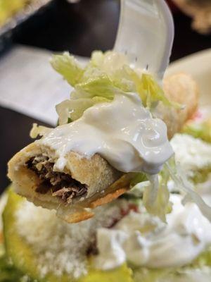 A fork holding a piece of the Tacos Dorados with the Shredded Beef inside.