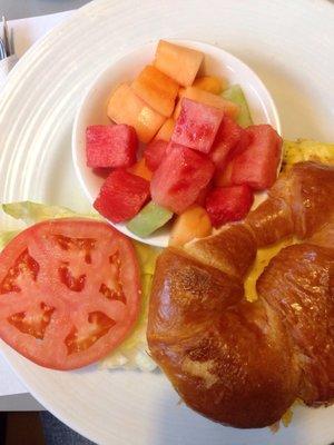 Breakfast croissant sandwich with fruit bowl