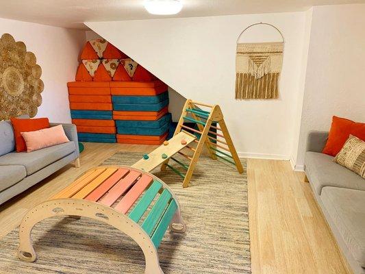 Our innermost playroom at Playlab Eagle Rock indoor playspace, set up with many Nugget Cushions, a Pikler triangle, and comfortable couches