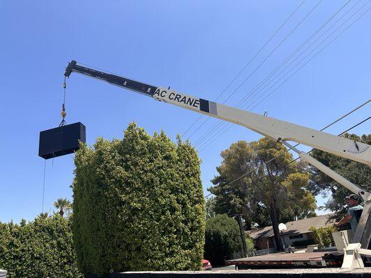 AC Crane lifting planter over large hedge.