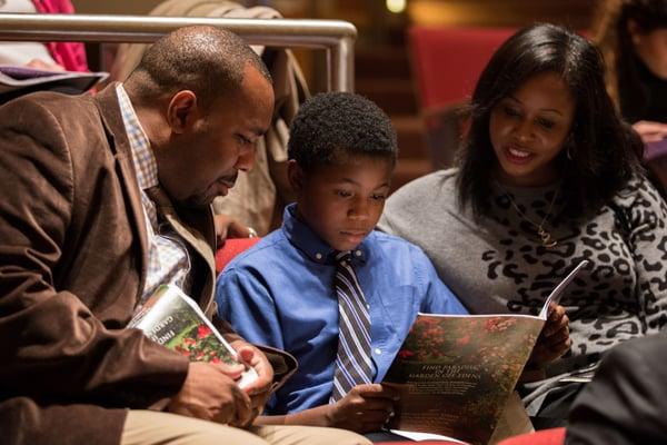 A family reads about the program during "Turning Points" concert. Photo by Elliot Mandel.