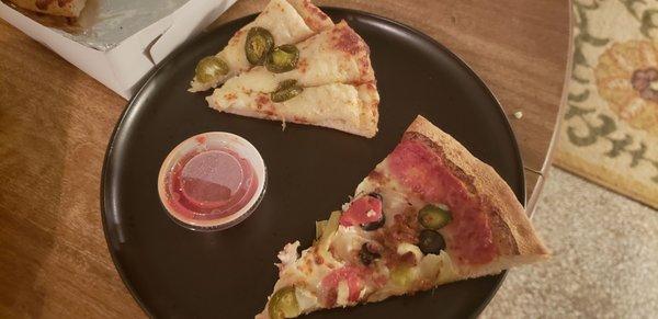 A slice of greek pizza with pepper sticks (jalapeno)