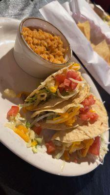 Three crispy beef $1 tacos with a side of rice on Taco Tuesday