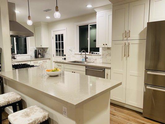 Spartan White with brass handles and knobs, Nuage quartz counters, Calacata Gold marble tile backsplash, September Fog paint (Lowe's)