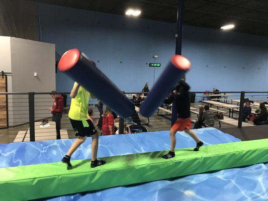 Jousting on a balance beam which is surrounded by by an air mattress