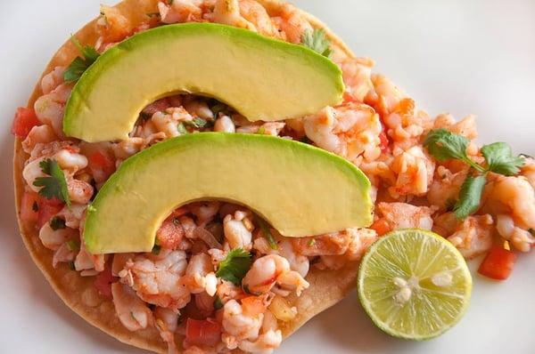 Tostada de Ceviche.
 Shrimp or fish,marinated in lime juice w/tomato, onion, cilantro, served on a corn tostada topped w/avocado