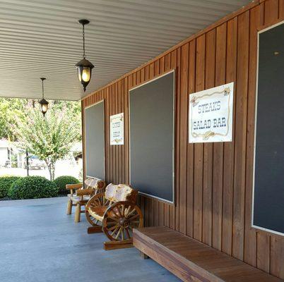 Some nice carved benches on a wide shaded front porch on which to sit awhile.