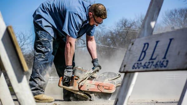 Matt of The Scottish Plumber saw-cutting parking lot to gain access to a broken sewer.