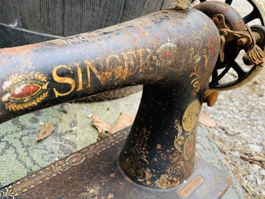 Singer sewing machine sitting out side with old rakes and windows makes me sad