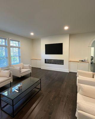 We custom-built this floor-to-ceiling wall niche, featuring a recessed 65″ TV, an 80″ electric fireplace, and side cabinets with countertops