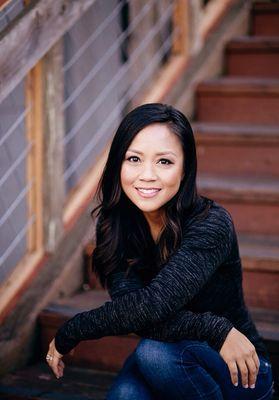 Monica Ramil smiles while she sits on stairs with her arms crossed and resting on her lap.