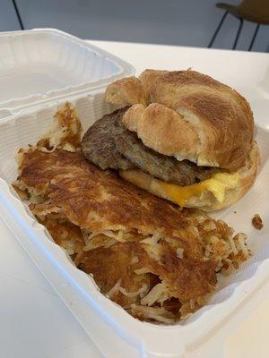 Sausage, Egg and Cheese Sandwich on a croissant with hash brown.