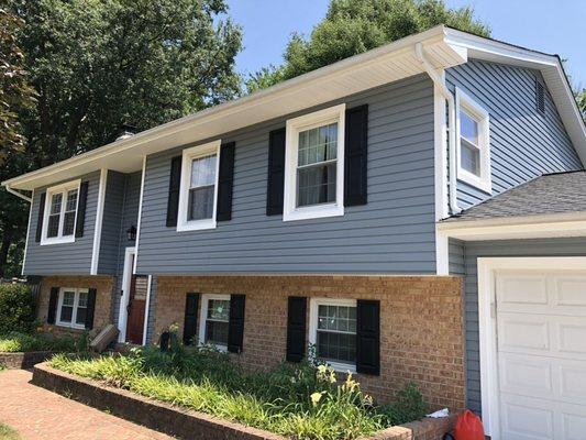 Straight lap vinyl siding in coastal blue with white trim. Black raised panel shutters. New white energy efficient windows.