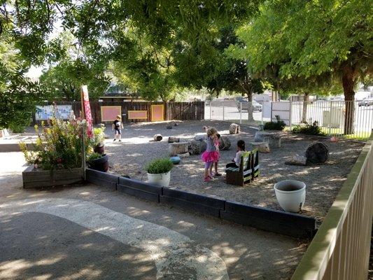 Calm outdoor play area where children can help grow plants and enjoy the many herbs and flowers in the garden