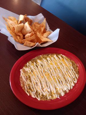 Bean dip with sour cream, cheese and green sauce. Flour chips on the side