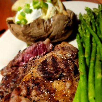 Rib eye medium rare with baked potato and asparagus.