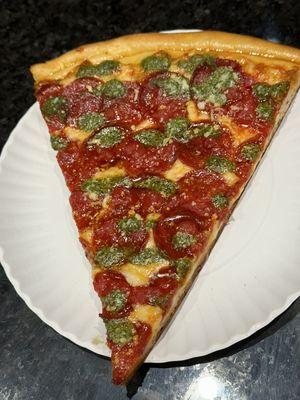 A slice of pesto pepperoni pizza..