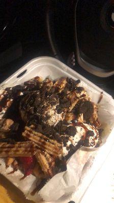 Funnel cake topped with Oreo ice cream, strawberries, banana, churros, chocolate syrup and cookie crumbles!! Yummy