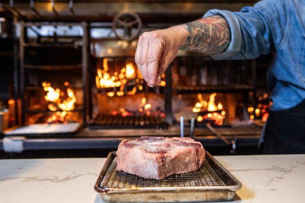 Preparing a steak in front of the live fire hearth