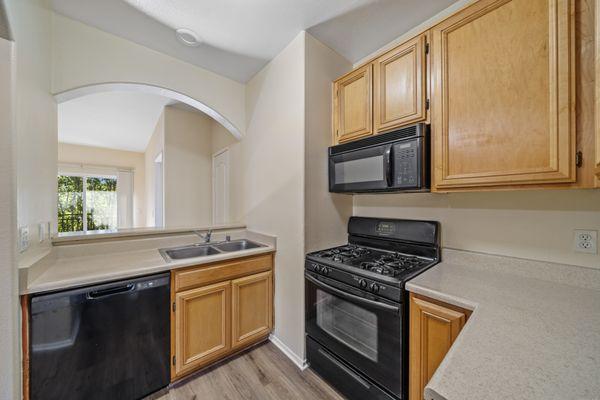 Modern kitchen with  gas stove, Tuscan half moon archway, stainless steel detailing and sleek slate grey countertops.