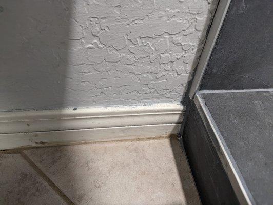 Schluter trim should go all the way to the floor. Instead, grout is slathered on. And this is how "clean" it was left.