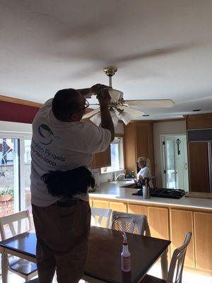 Jefferey cleaning ceiling fan and Trina doing final touches in the background.