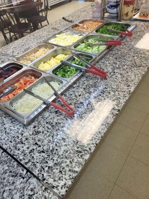 The salad bar side of the buffet has fresh sliced pineapple,  everything to build a house salad,  chicken salad,  potatoes salad, Pico