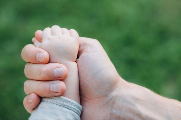 The little hand is held in the big hand. Daughter and Dad's time