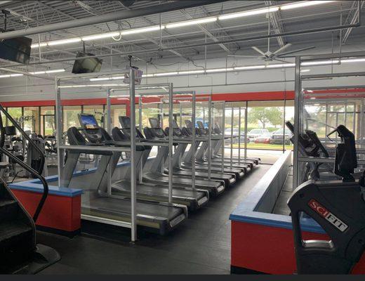 Treadmills with partitions and TVs.