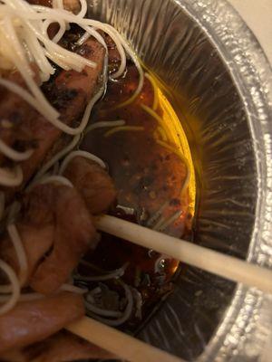 Chicken thighs out of a deep fryer swimming in oil.