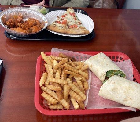 Wings and pizza and a wrap with fries.