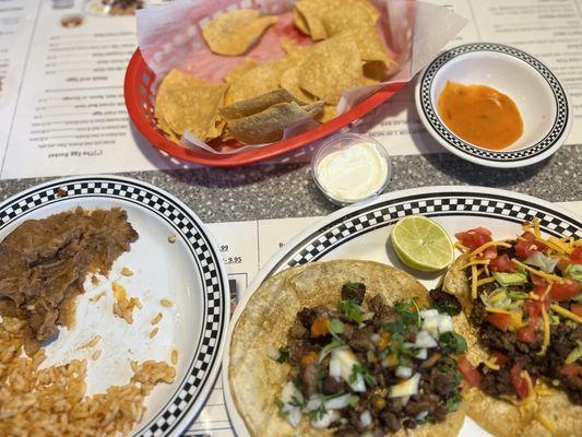 Two tacos, chips with salsa, beans and rice